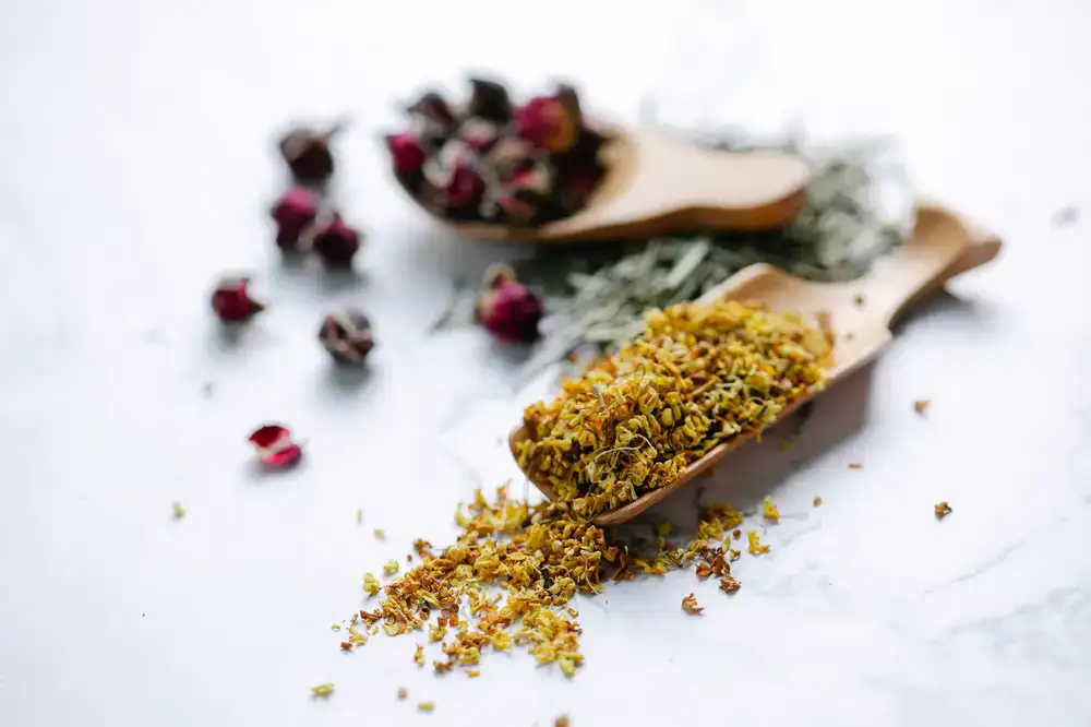 A wooden scoop measuring dried botanicals for a bespoke blend