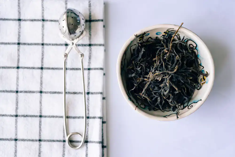 Detailed view of dried loose leaf tea and delicate ceramic cups
